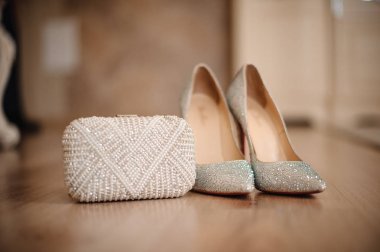 shoes of the bride with shiny pebbles stand next to a white clutch clipart