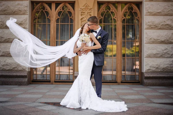 Stilvolle Groomis werden die charmante Braut auf dem Hintergrund von Holztüren küssen — Stockfoto