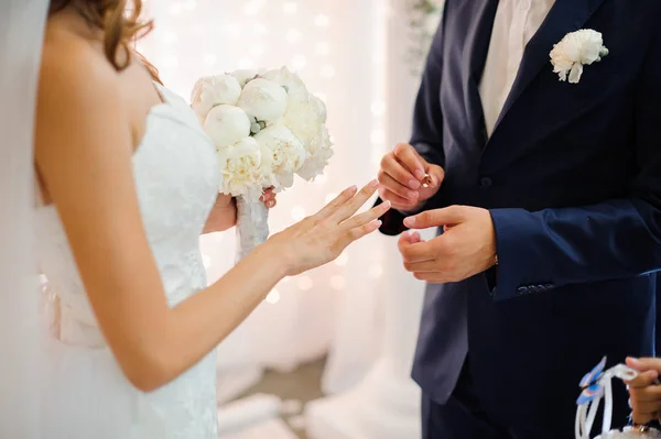 Noivo coloca em um anel de casamento de ouro no dedo de uma noiva bonita — Fotografia de Stock