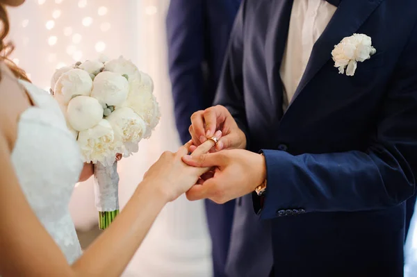 Noivo coloca uma aliança de casamento no dedo de uma noiva bonita — Fotografia de Stock