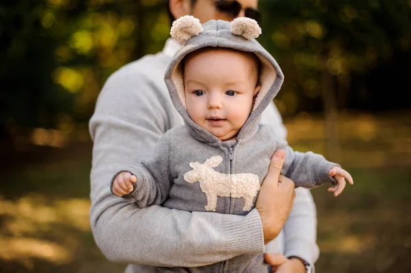 Chlapeček v legračním oblečení, na rukou tatínek venku — Stock fotografie