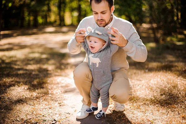 Pai pega por mãos seu filho rindo ao ar livre — Fotografia de Stock