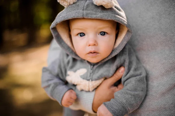 Μικρό αγόρι με σκεπτικός γκρι μάτια μοιάζει συνεδρίαση προσεκτικά τα χέρια πατέρες — Φωτογραφία Αρχείου