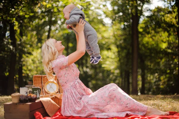 Blonde moeder gekleed in een jurk die spelen met een baby — Stockfoto