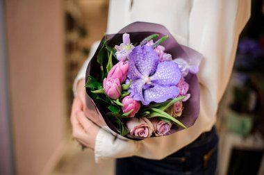 Bir buket çiçek mor kağıt ile beyaz bir bluz giymiş kadın