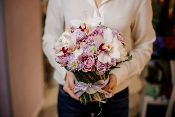 Mulher vestida com uma blusa branca segurando um buquê de flores — Fotografia de Stock