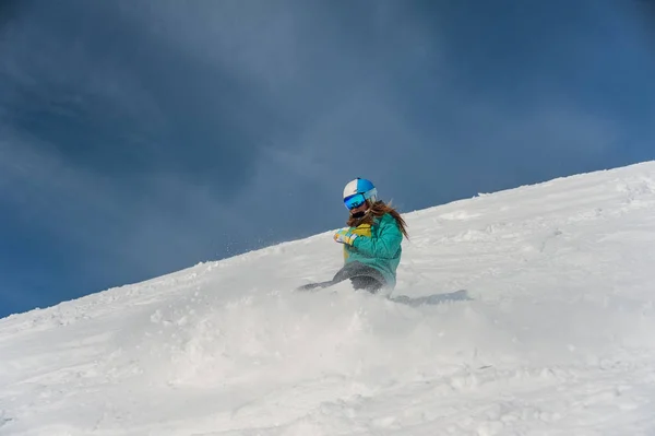 Mulher snowboarder em capacete descendo a encosta da montanha — Fotografia de Stock