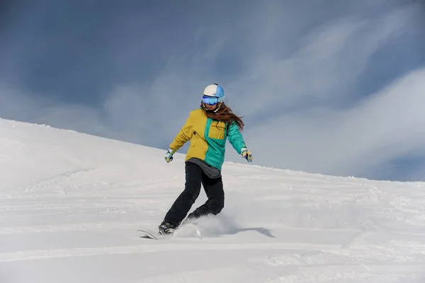 Жінка сноубордистка в шоломі і окулярах їде по горах — стокове фото