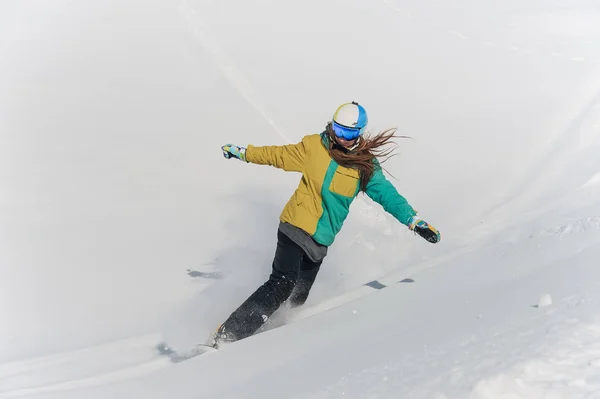 Snowboarder feminino em roupas esportivas coloridas e capacete andando para baixo — Fotografia de Stock