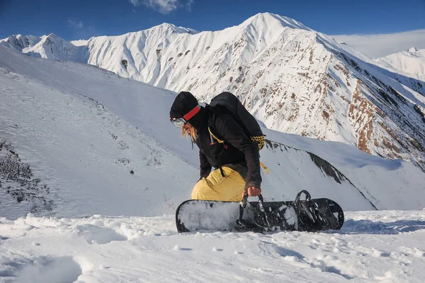 Freeride snowboarder segurando uma placa no fundo das montanhas — Fotografia de Stock