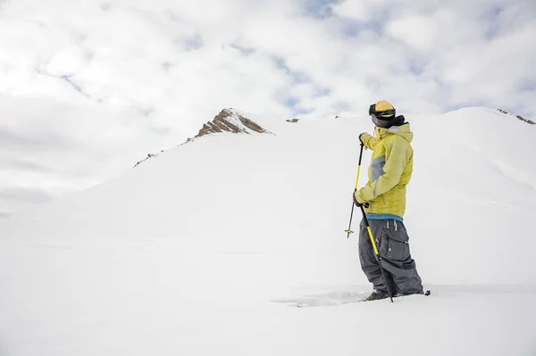 Freeride snowboarder vestido de sportswear amarelo olhando para a montanha — Fotografia de Stock