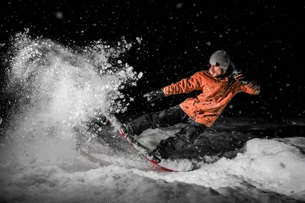 Jovem freeride snowboarder pulando na neve à noite — Fotografia de Stock