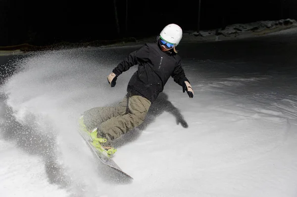 Jovem snowboarder descendo a encosta da montanha à noite — Fotografia de Stock