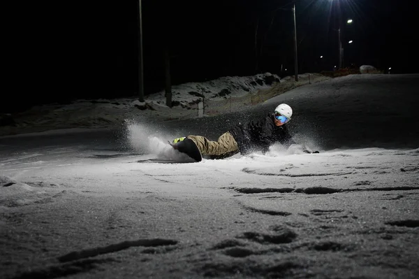 Snowboarder ativo cavalgando pela encosta da montanha à noite — Fotografia de Stock