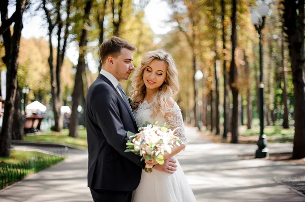 Retrato de un novio abrazando a una novia rubia en el parque — Foto de Stock