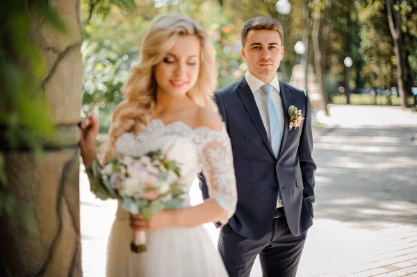 Schöner Bräutigam, der auf dem Hintergrund der Braut steht — Stockfoto