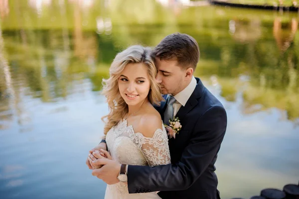 Joven y atractiva novia con novio en la orilla del río — Foto de Stock