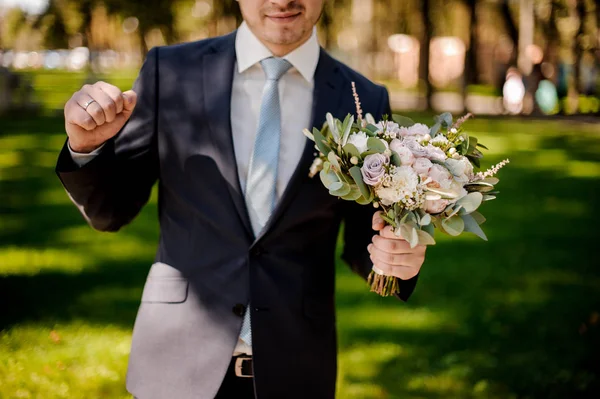 Damat gülümseyen çiçeklerle düğün takım elbise giymiş — Stok fotoğraf