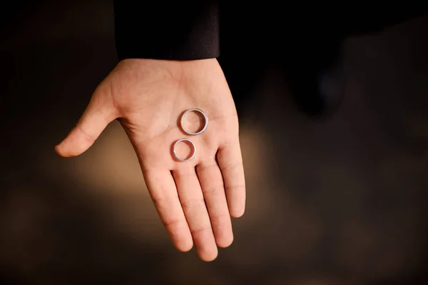 Close up photo of male hand holding wedding rings — Stock Photo, Image