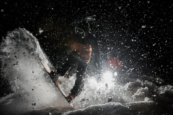 在黑暗下的雪下, 男子惊人地骑滑雪板 — 图库照片