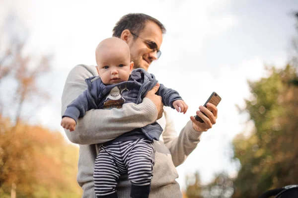 Otec držel malého syna a kontrola telefon — Stock fotografie