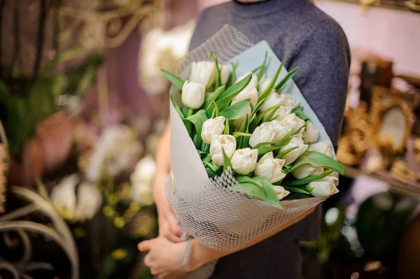 Жінка тримає букет білих тюльпанів, загорнутий у папір — стокове фото