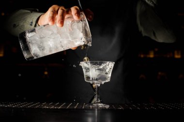 Şeffaf bir alkollü kokteyl ile buz gl içine dökme barmen