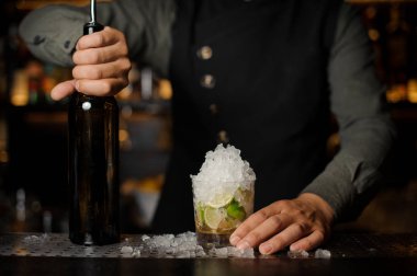 Holding bir şişe ve bardak mojito barmen