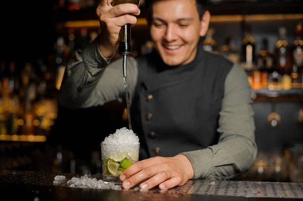 Cantinero sonriente vertiendo jarabe dulce en el mojito — Foto de Stock