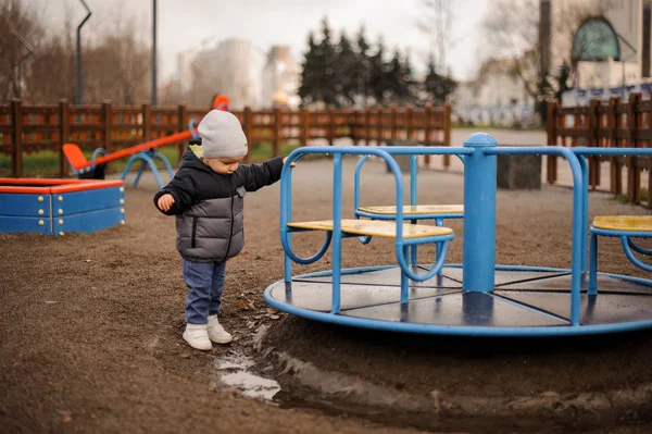 Anak kecil berpakaian topi hangat dan jaket bermain di dekat mobil — Stok Foto