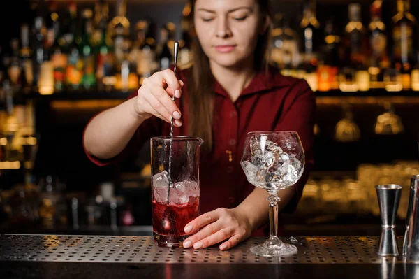 Bonito barman feminino mexendo bebida alcoólica doce com gelo — Fotografia de Stock