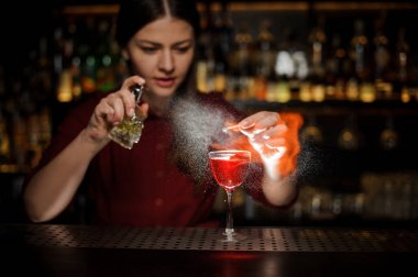 Aperol şırınga ile lenen bir viski kokteyli ile bir kokteyl cam yağmurlama ve dumanlı bir notu çubuğunda oluşturma kadın barmen sayaç