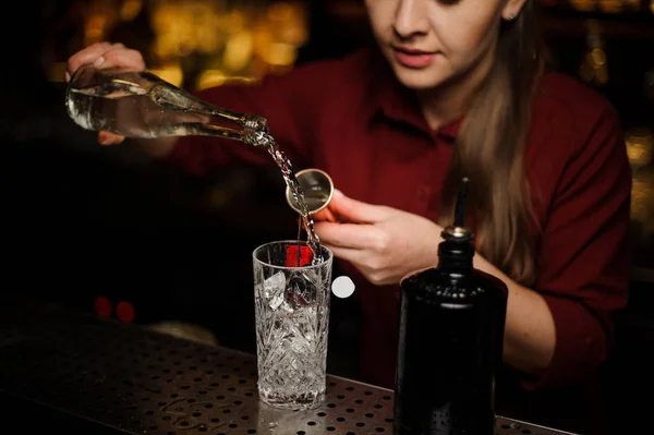 Mulher barman derramando gin em uma taça de coquetel — Fotografia de Stock