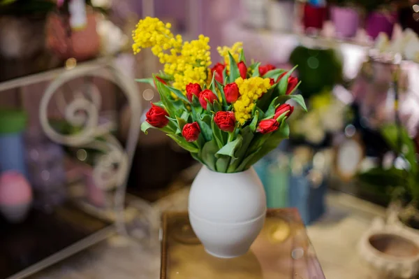 Hermosos tulipanes rojos y mimosa amarilla en un jarrón azul — Foto de Stock