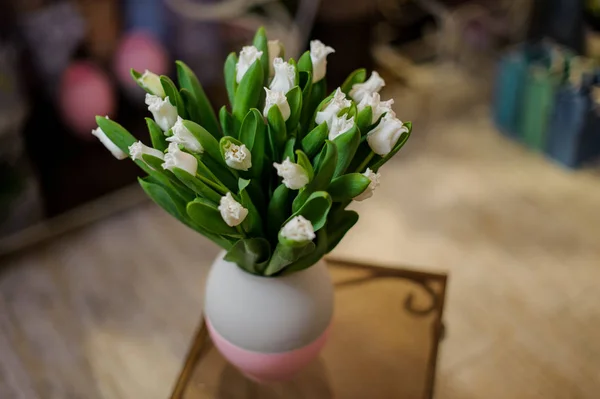 Schöne weiße Tulpen stehen in einer blauen und rosa Vase — Stockfoto