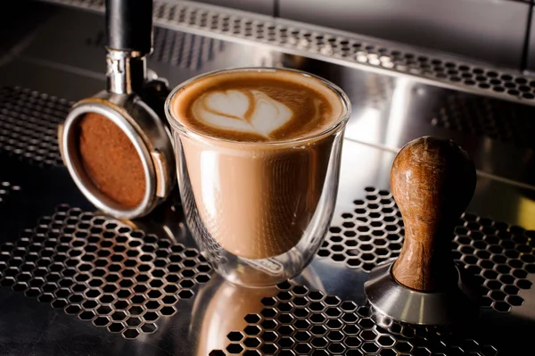 Caffè tamper e tazza di caffè riempito con latte decorato sul bancone — Foto Stock