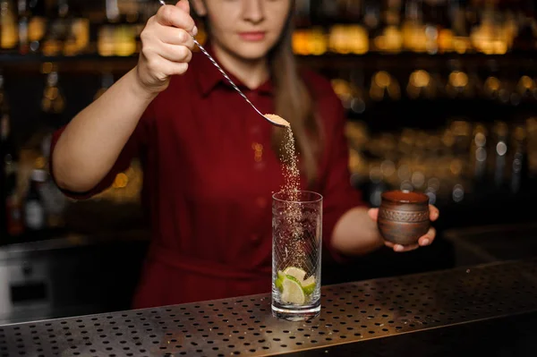 Cantinera hembra vertiendo en un vaso una cucharada de azúcar de caña — Foto de Stock