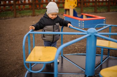 Küçük çocuk bir sıcak şapka ve carous üzerinde sürme ceket giymiş