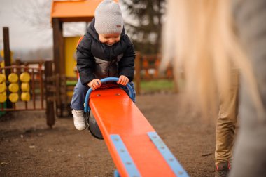 Küçük çocuk bir sıcak ceket ve salıncakta sürme şapka giymiş