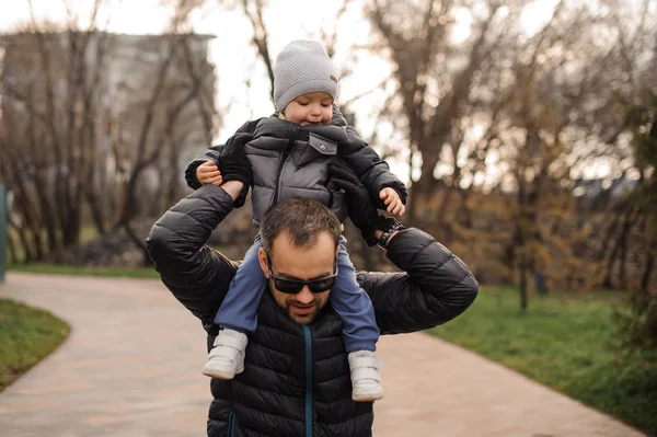 Otec v brýlích nošení malého syna na ramenou — Stock fotografie