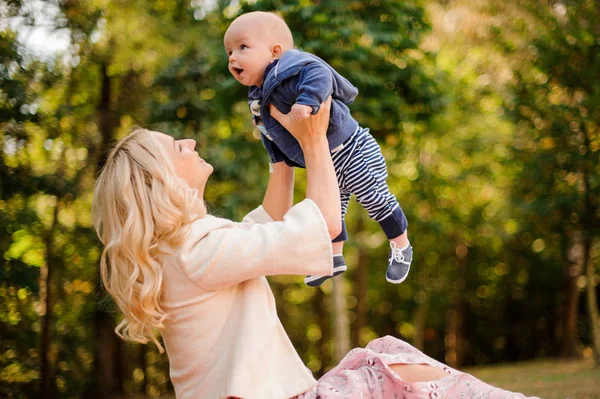 Mãe brincando com um bebê bonito filho em um parque — Fotografia de Stock