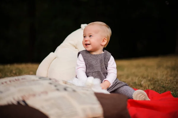 Niña riendo sentada en una manta en el parque — Foto de Stock