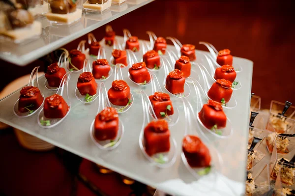 Uppsättning av salta små aptitretare i en röd glasyr dekorerad med soltorkad tomat och microgreens — Stockfoto