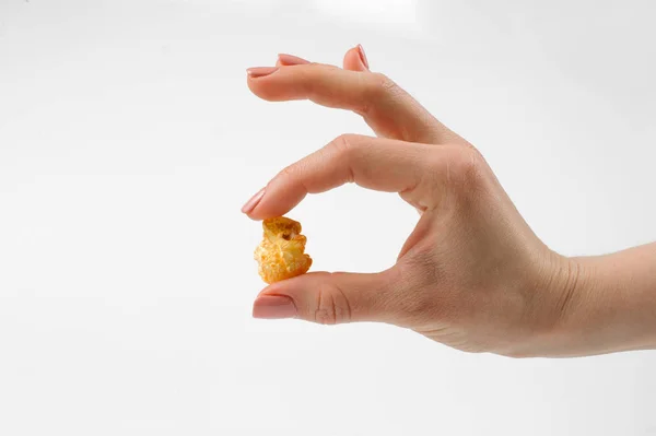 Female hand holds one grain of popcorn on a white background — Stock Photo, Image