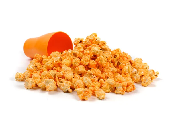 Luchtige korrels van popcorn verspreid van een Oranje glazen op een witte achtergrond — Stockfoto