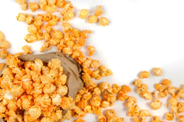 Grote korrels van gele popcorn in een ambacht inpakken en verspreid op een witte achtergrond — Stockfoto