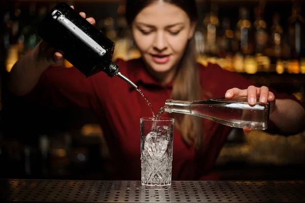 Barmann Mädchen bereitet einen alkoholischen Cocktail Caipirinha, Gießen aus zwei Flaschen — Stockfoto