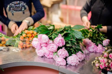 Çiçekçi gül renkli peonies ve turuncu Lale iki demetleri yapma