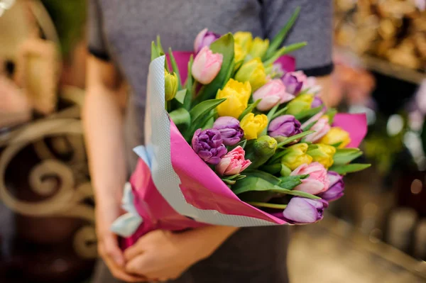 Дівчина тримає букет з рожевих, жовтих і фіолетових тюльпанів — стокове фото