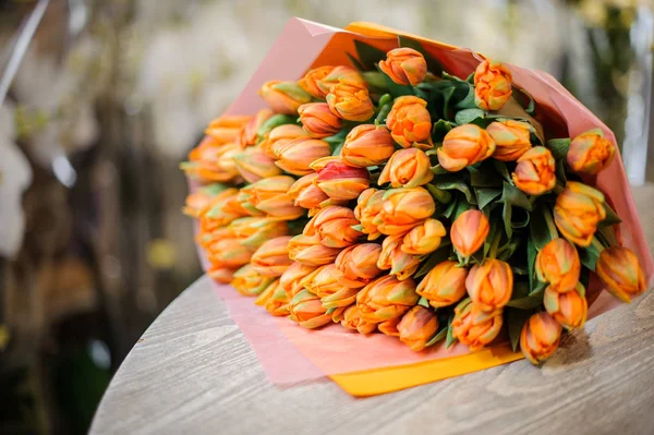 Krásná kytice z oranžové tulipány ležící na stole — Stock fotografie